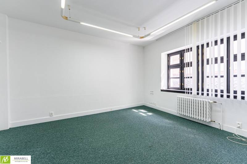 Klimatizované kancelárie v centre mesta na Michalskej ulici  - Kancelária s bielymi stenami, zeleným kobercom a oknami s vertikálnymi žalúziami.