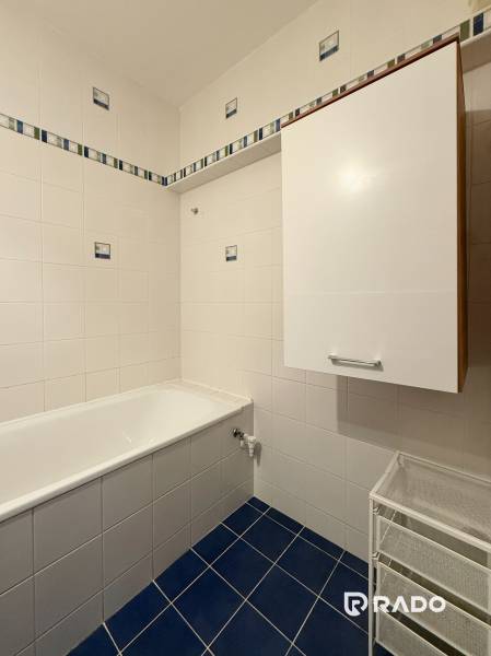 Priestranný 3-izbový byt s balkónom 68 m² Belinského - Kúpeľňa v 3-izbovom byte s bielymi stenami a tmavomodrou dlážkou.