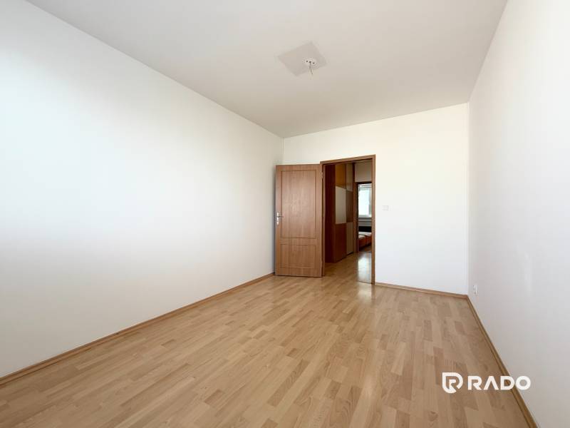 Priestranný 3-izbový byt s balkónom 68 m² Belinského - Prázdna izba s drevenou podlahou a zatvorenými dverami v 3-izbovom byte.
