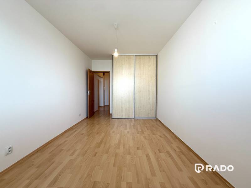 Priestranný 3-izbový byt s balkónom 68 m² Belinského - Izba s drevenou podlahou a veľkou vstavanou skriňou v 3-izbovom byte.