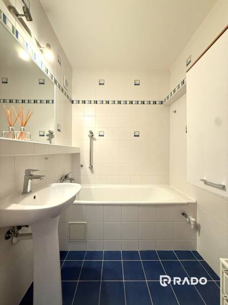 Priestranný 3-izbový byt s balkónom 68 m² Belinského - Kúpeľňa s bielymi obkladačkami a modrou podlahou v 3-izbovom byte.