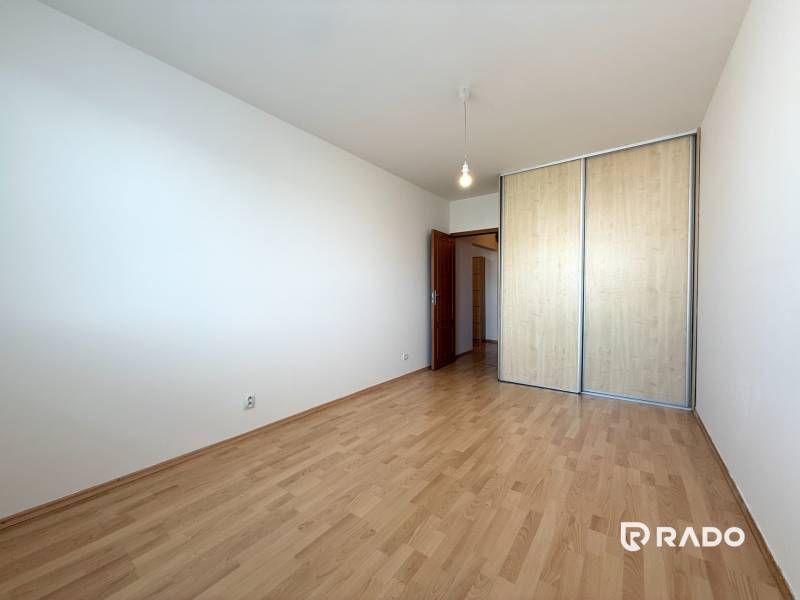 Priestranný 3-izbový byt s balkónom 68 m² Belinského - Prázdna izba s drevenou podlahou a vstavanou skriňou v 3-izbovom byte.