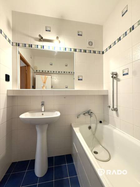 Priestranný 3-izbový byt s balkónom 68 m² Belinského - Kúpeľňa v 3-izbovom byte s bielymi obkladačkami, vaňou a umývadlom.