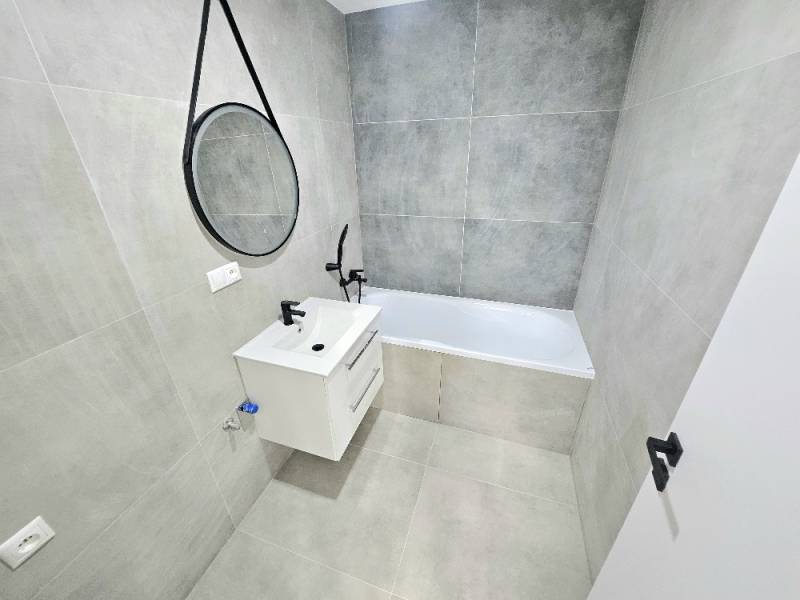 3 izbový byt Bánovce nad Bebravou / CENTRUM- STRED / 56 m2 / NOVÁ REKO - Kúpeľňa v 3-izbovom byte s vaňou, umývadlom a zrkadlom na stene.
