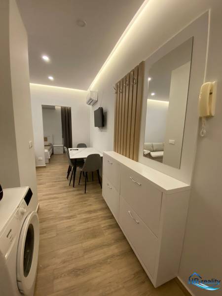 Sarandë - novozariadený apartmán s výhľadom na more - Chodba rekreačného apartmánu s práčkou, zrkadlom a jedálenským stolom.