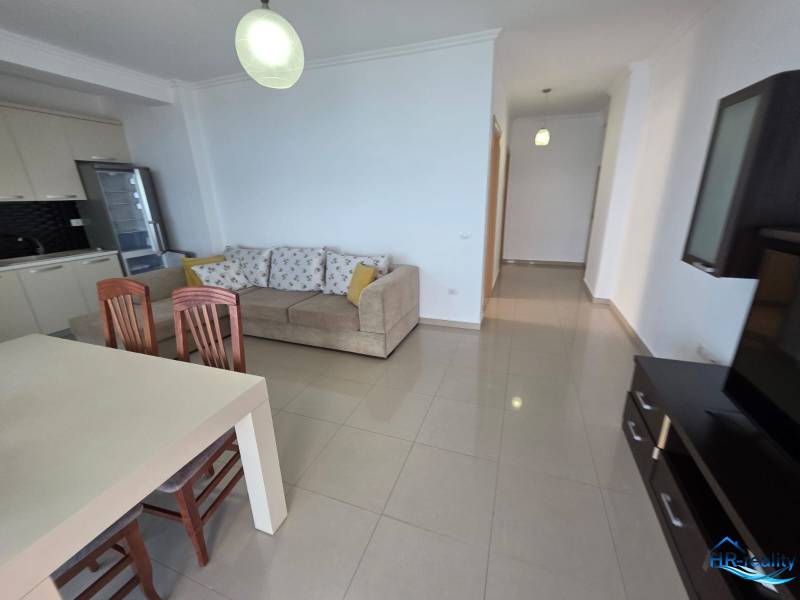 Sarandë - zariadený apartmán s otvoreným výhľadom na more - Svetlá obývačka s kuchynským kútom, pohovkou a jedálenským stolom v Rekreačnom apartmáne.