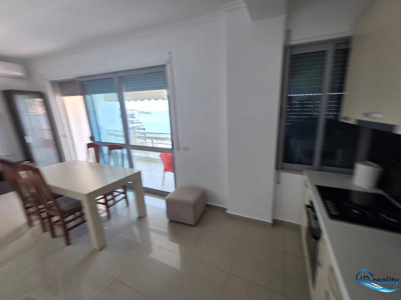 Sarandë - zariadený apartmán s otvoreným výhľadom na more - Jedálenský kút s výhľadom na more v rekreačnom apartmáne, svetlé interiérové zariadenie.