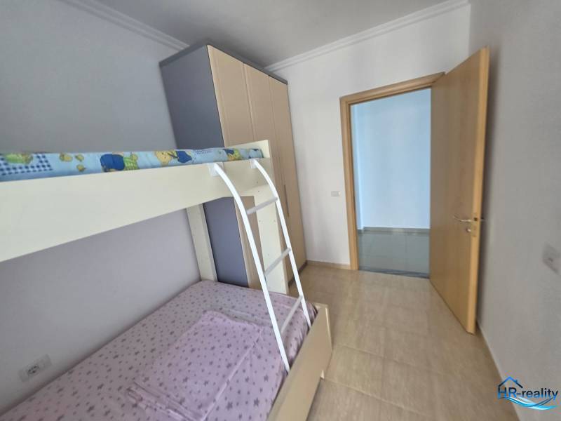 Sarandë - zariadený apartmán s otvoreným výhľadom na more - Detská izba s poschodovou posteľou v rekreačnom apartmáne má svetlé steny a podlahy.