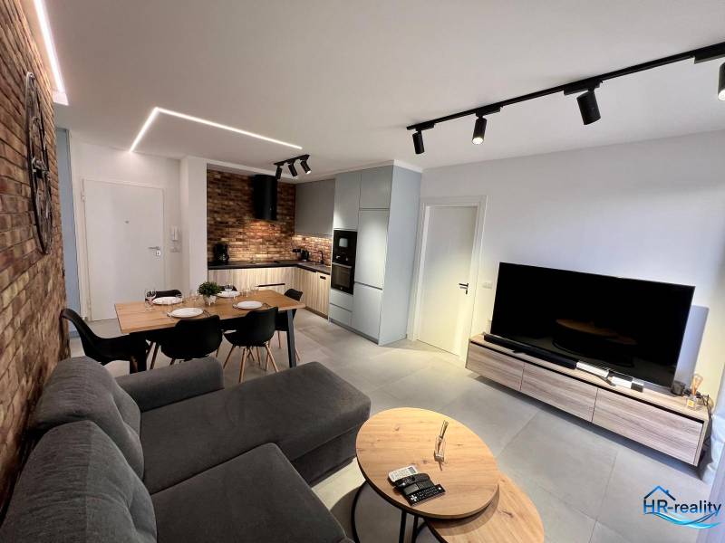 Sarandë - zariadený apartmán, výhľad na more, garážové státie - Obývačka rekreačného apartmánu je vybavená kuchyňou, jedálenským stolom a pohodlnou pohovkou.