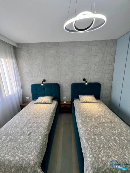 Sarandë - zariadený apartmán, výhľad na more, garážové státie - Dvojlôžková spálňa s geometrickou tapetou a moderným osvetlením v rekreačnom apartmáne.