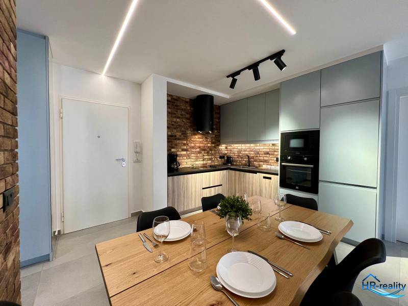 Sarandë - zariadený apartmán, výhľad na more, garážové státie - Kuchyňa v Rekreačnom apartmáne s jedálenským stolom, tehlovým obkladom a modernými spotrebičmi.