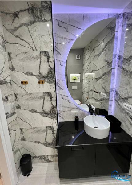 Sarandë - zariadený apartmán, výhľad na more, garážové státie - Kúpeľňa v Rekreačnom apartmáne s okrúhlym zrkadlom a elegantnými obkladmi.