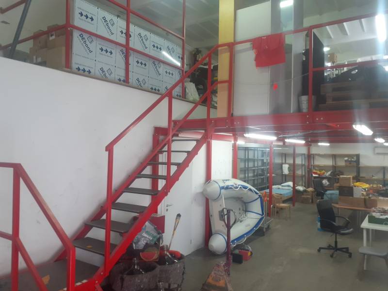 Prenájom skladu 150 m2 pri Zlatých pieskoch na Studenej ul. - Interiér skladu s regálmi, člnom a červeným schodiskom.
