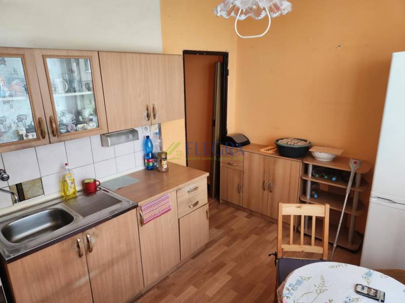 REZERVOVANÝ- 1-izbový byt, Košice, Ružová ulica - Kuchyňa v 1-izbovom byte s drevenými skrinkami, stolom a chladničkou.