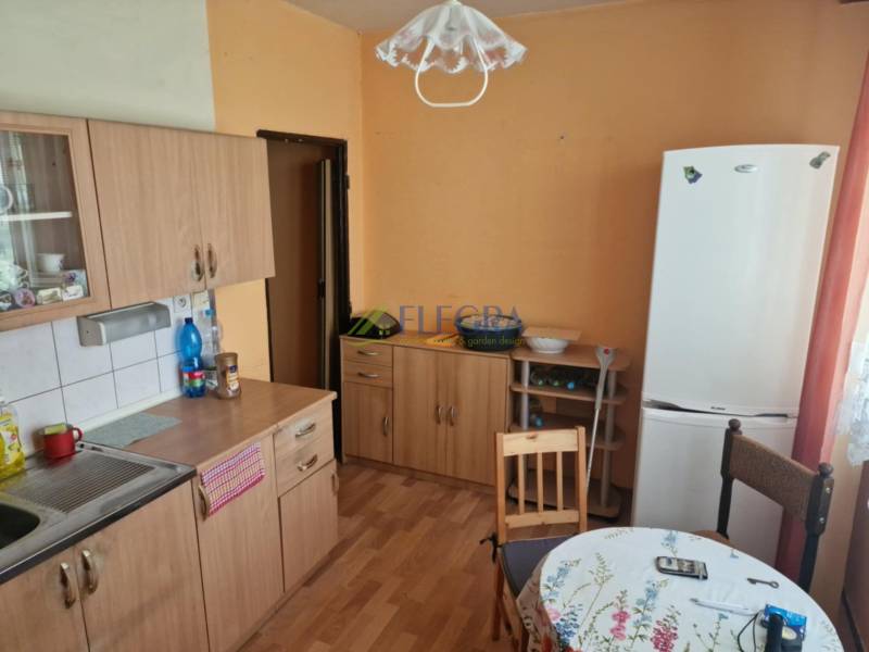 REZERVOVANÝ- 1-izbový byt, Košice, Ružová ulica - Kuchyňa v 1-izbovom byte s drevenými skrinkami, stolom a chladničkou.