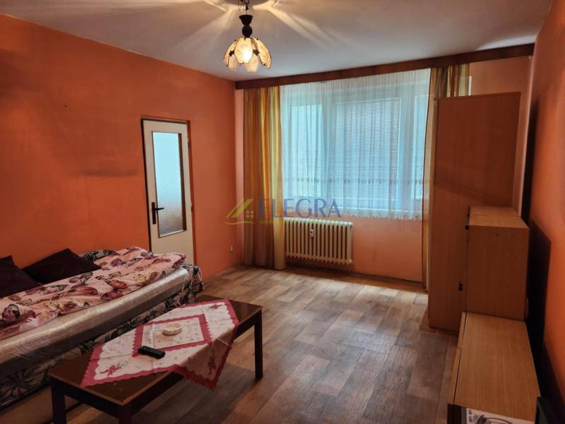 REZERVOVANÝ- 1-izbový byt, Košice, Ružová ulica - Obývacia izba v 1-izbovom byte so sedačkou, stolíkom a oknom s radiátorom.