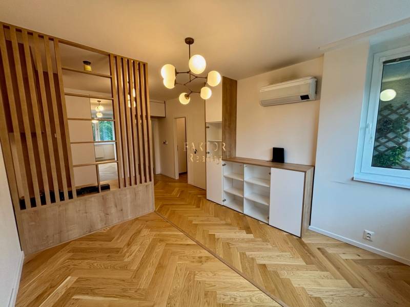 Kompletne zrekonštruovaný a premyslene zariadený byt pre tých, ktorí h - Interiér 2-izbového bytu s drevenou podlahou, deliacou stenou a moderným osvetlením.