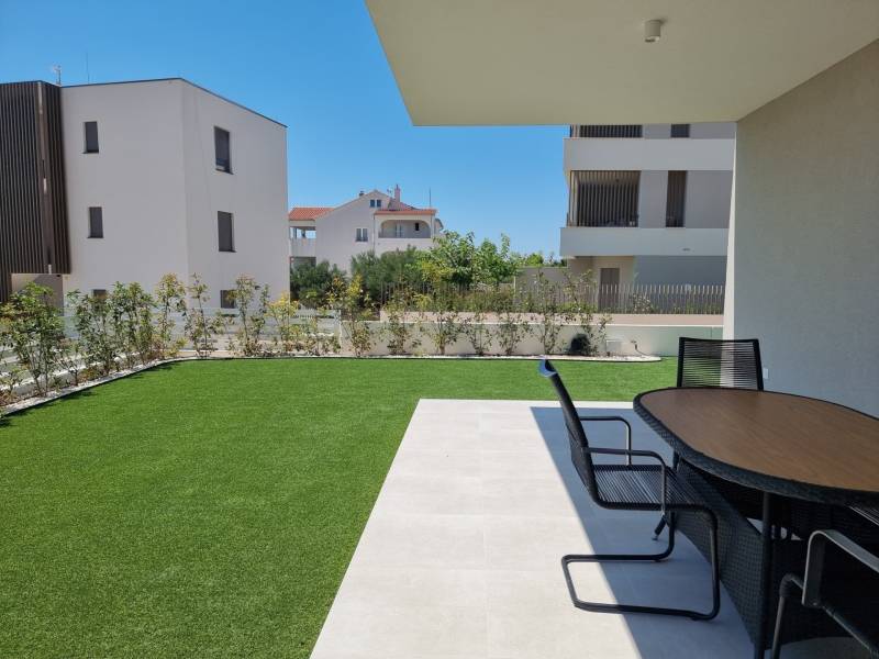 CHORVÁTSKO - Pekné apartmány 350m od pláže (S1) - VODICE - Záhrada 4-izbového bytu vo Vodiciach s terasou a moderným stolom na tráve.