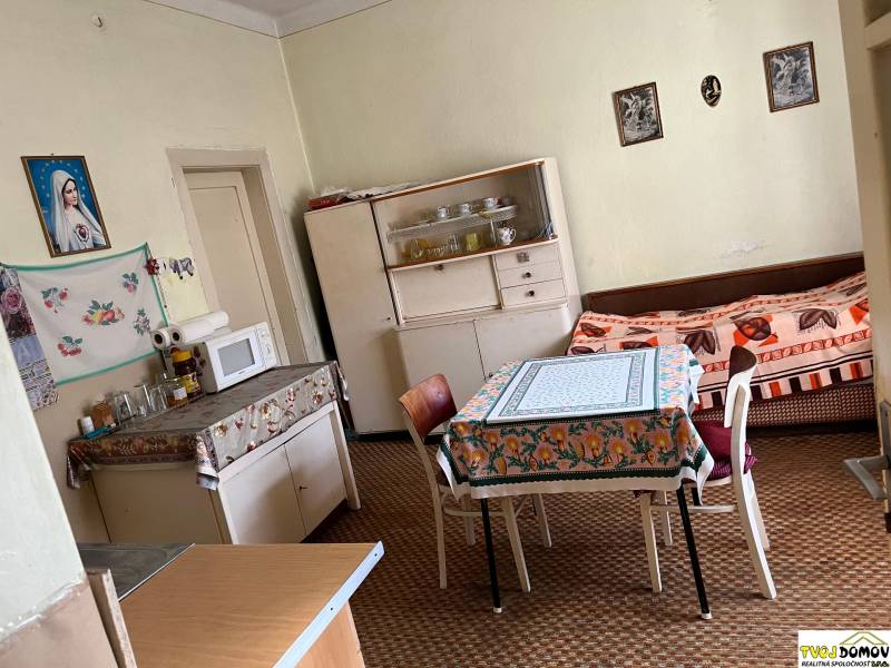 Rodinný dom v Detve na predaj - Kuchyňa v rodinnom dome s jedálenským stolom, mikrovlnkou a pohovkou.