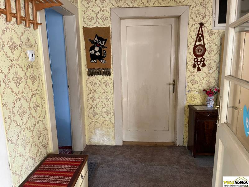Rodinný dom v Detve na predaj - Chodba v rodinnom dome s tapetami, dreveným nábytkom a dekoráciami na stenách.