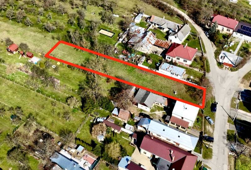 Moravské Lieskové - STAVEBNÝ POZEMOK s investičným potenciálom - Letecký pohľad na pozemok vo výstavbe domov v Moravských Lieskových, zvýraznený červeným obrysom.