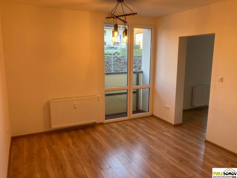 Na prenájom - príjemný 3i byt s balkóm v Detve -kompletná rekoštrukcia - Izba s drevenou podlahou a veľkým oknom v 3-izbovom byte, jednoduché osvetlenie.