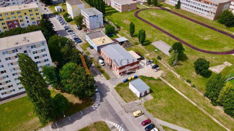 INVESTIČNÝ KOMERČNÝ OBJEKT | TOPOĽČANY  - Letecký pohľad na obchodné priestory na Janka Matušku v Topoľčanoch, obklopené bytovkami a športoviskom.