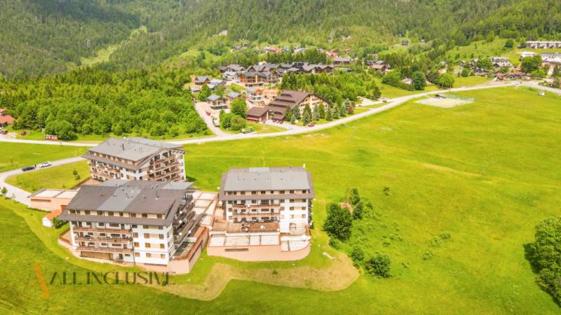 PRIESTRANNÝ 3 IZBOVÝ BYT S TERASOU | DONOVALY  - Letecký pohľad na apartmány blízko ulice Panorama v Donovaloch, obklopené zeleňou a horami.