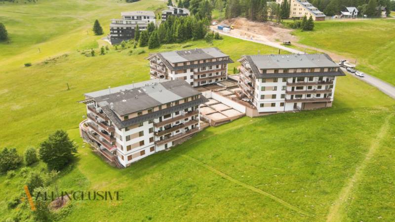 PRIESTRANNÝ 3 IZBOVÝ BYT S TERASOU | DONOVALY  - Pohľad na apartmánové budovy na ulici Panorama v Donovaloch obklopené zelenou krajinou.