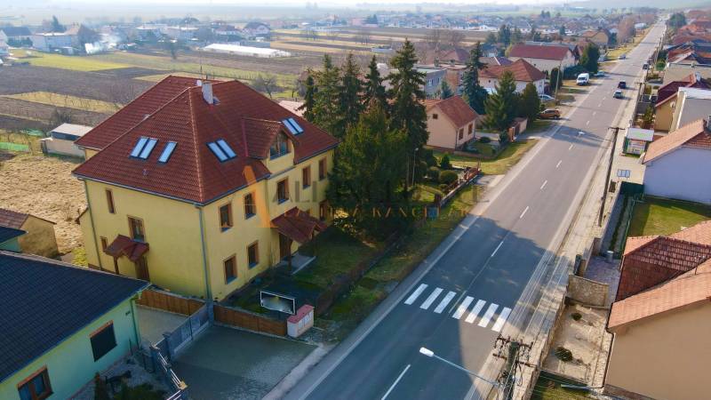  POLYFUNKČNÝ OBJEKT | CHRABRANY | TOPOĽČANY - Budova na ulici Chrabrany v Topoľčanoch, obklopená domami a stromami, pri hlavnej ceste.