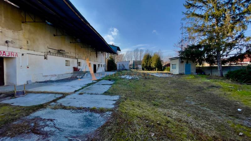 AREÁL | SKLAD | VÝROBNÁ HALA | KOVARCE | TOPOĽČANY - Výrobné priestory na Hlavnej ulici v Kovarciach so zeleňou a budovami na dvore.