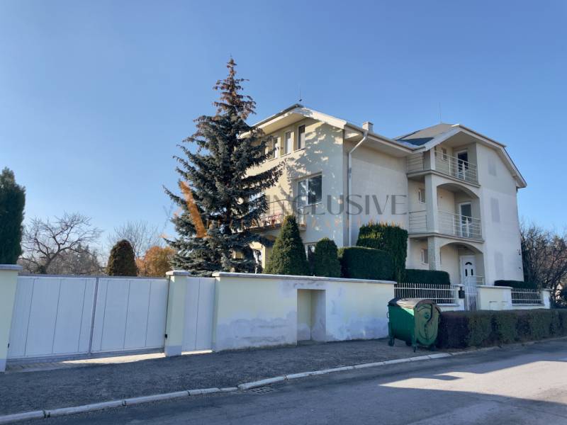 UBYTOVANIE PRE FIRMY - APARTMÁNY | TOPOĽČANY - Vila na Športovcov ulici v Topoľčanoch so stromami a odpadkovým kontajnerom.