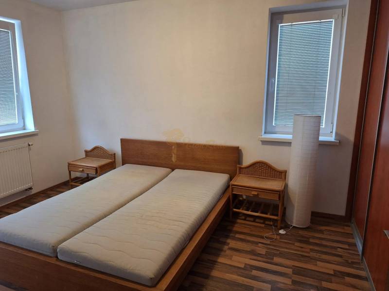 2-izb. byt, Pezinok, sídlisko Muškát - Spálňa v 2-izbovom byte s drevenou posteľou a nočnými stolíkmi.