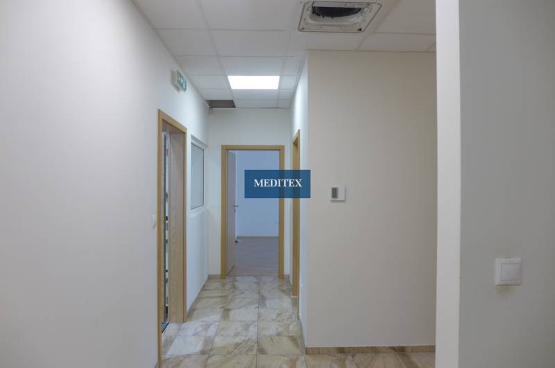 Sklad na prenájom s kanceláriami a zázemím o ploche 370 m2 - Biela chodba s dlažbou, drevenými dverami a osvetlením v areáli skladov a hál.