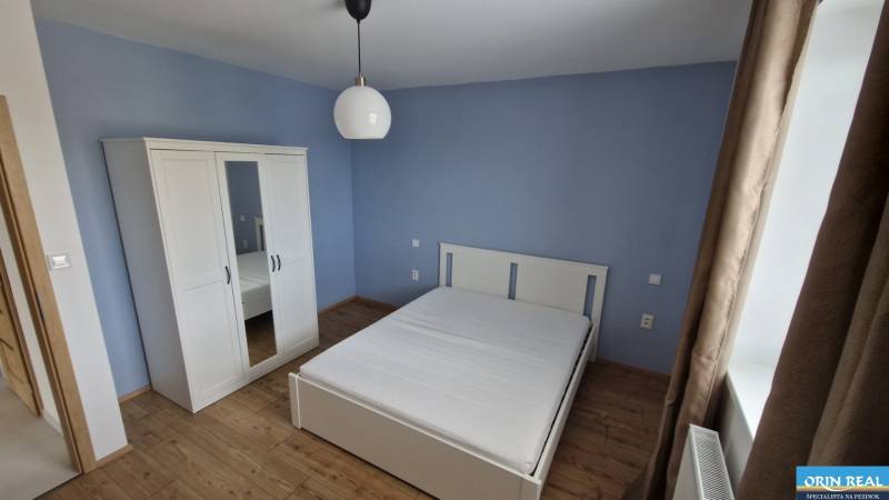 NOVÝ ZARIADENÝ BYT NA Muškáte - Spálňa v 2-izbovom byte s posteľou, šatníkom a drevenou podlahou.