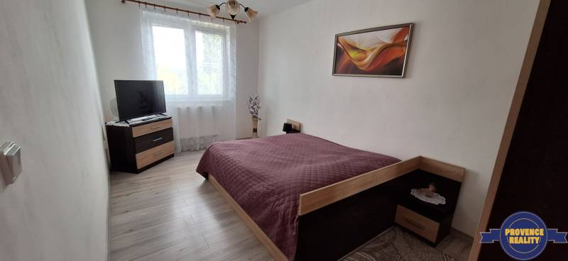 PREDAJ: 3 izbový byt s loggiou - Komárno, č. Ďulov Dvor - Spálňa v 3-izbovom byte s posteľou, televízorom a dekoráciou na stene.