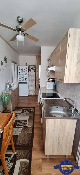 PREDAJ: 3 izbový byt s loggiou - Komárno, č. Ďulov Dvor - Kuchyňa v 3-izbovom byte s dreveným nábytkom a stropným ventilátorom.