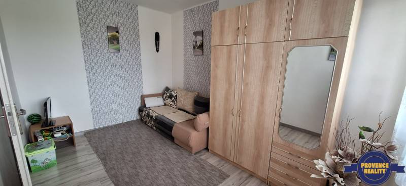 PREDAJ: 3 izbový byt s loggiou - Komárno, č. Ďulov Dvor - Obývacia izba v 3-izbovom byte s pohovkou, skriňou a dekoráciami na stene.