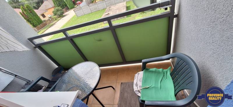 PREDAJ: 3 izbový byt s loggiou - Komárno, č. Ďulov Dvor - Balkón 3-izbového bytu s plastovou stoličkou a malým skleneným stolíkom.