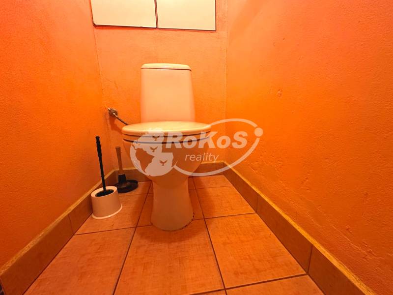 PRENÁJOM - 3 izbový byt s balkónom, Šafárikova ulica, Rožňava - Oranžová toaleta v 3-izbovom byte so záchodovou kefou v rohu miestnosti.