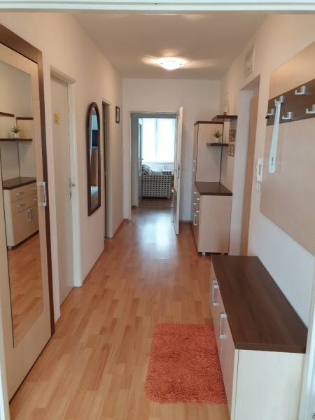 PRENÁJOM - 4-izbový byt, Nitra, Južná ulica - Chodba 4-izbového bytu s drevenou podlahou, zrkadlom a skrinkami na stene.