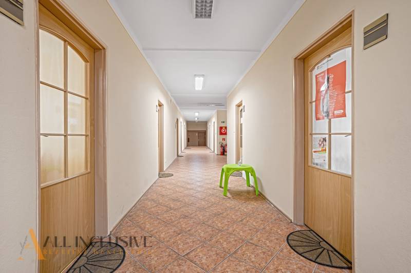 NA PRENÁJOM KANCELÁRSKE PRIESTORY V CENTRE MESTA D.S. - Chodba s dverami, dlažbou a zelenou stoličkou v kanceláriách.