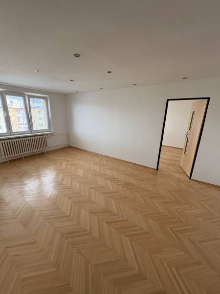 2-izbový byt s 1 veľkým balkónom a 1 menším balkónom v Novej Dubnici. - Izba s parketovou podlahou, bielymi stenami a oknami, súčasť 2-izbového bytu.