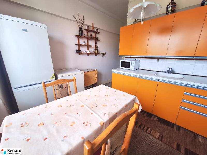 REZERVOVANÝ 2 IZBOVÝ TEHLOVÝ BYT, BALKÓN, ŠIRŠIE CENTRUM, PREŠOV - Kuchyňa v 2-izbovom byte s oranžovou linkou, bielou chladničkou a jedálenským stolom.