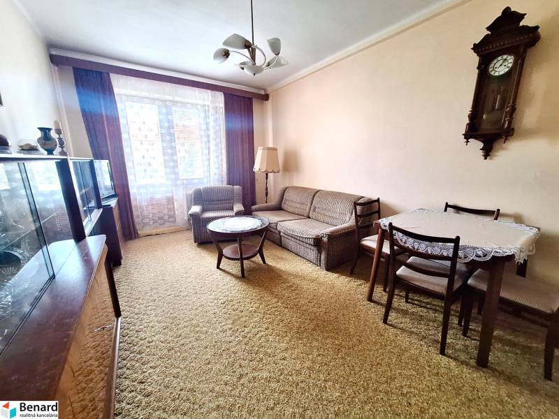 REZERVOVANÝ 2 IZBOVÝ TEHLOVÝ BYT, BALKÓN, ŠIRŠIE CENTRUM, PREŠOV - Obývačka v 2-izbovom byte so sedacou súpravou, stolom a starožitnými hodinami na stene.