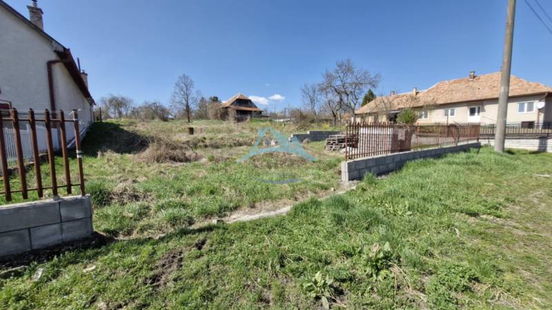 Pozemok (2394 m2) v Obeckove, okres Veľký Krtíš. - Pozemok na bývanie v Obeckove s trávnatou plochou a susednými domami.