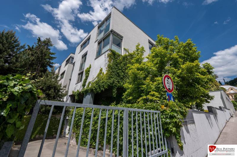 Exkluzívny 3 izbový byt, ul.Timravina, 147 m2, výhľad, parkovanie,BAI - Budova v Bratislave - Staré Mesto s popínavými rastlinami a modrou oblohou, vedľa dopravnej značky.