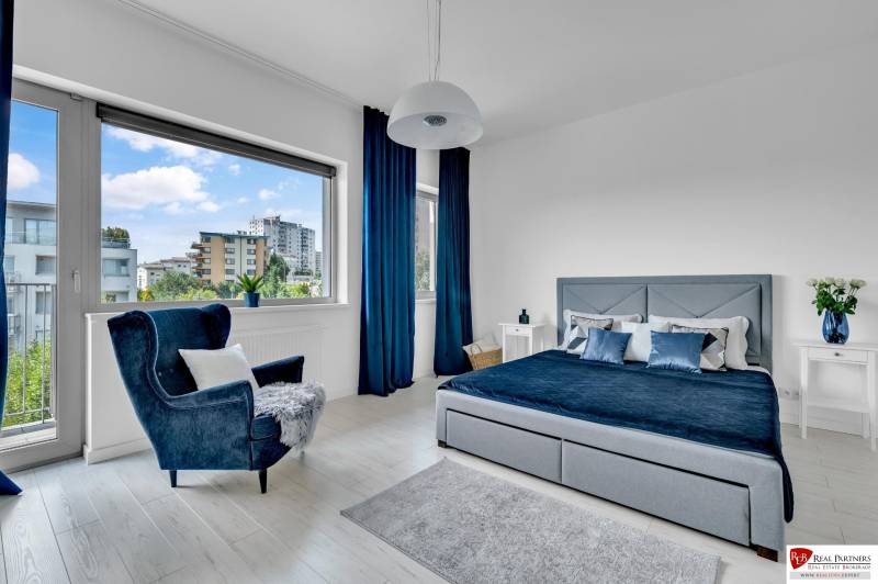 Predaj, Luxusný 4 izbový byt, 180 m2 + 25 m2, Condominium Renaissance - Svetlá spálňa v 4-izbovom byte s veľkým oknom, modrými závesmi a pohodlným kreslom.