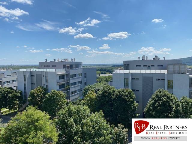 Predaj, Luxusný 4 izbový byt, 180 m2 + 25 m2, Condominium Renaissance - Pohľad na moderné bytovky v Bratislave - Karlovej Vsi obklopené zeleňou a modrou oblohou.