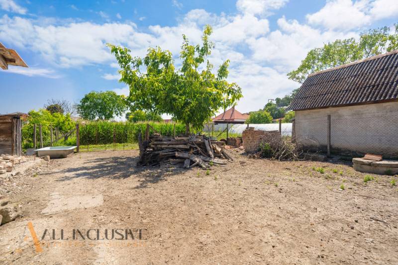 NA PREDAJ 4-IZBOVÝ RODINNÝ DOM V JAHODNEJ - Dvor s kopou dreva pri rodinnom dome v Jahodnej, s modrou oblohou.